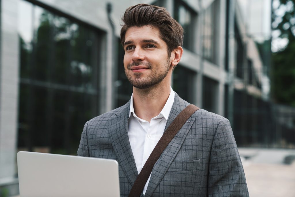 Optimistic handsome business man using laptop